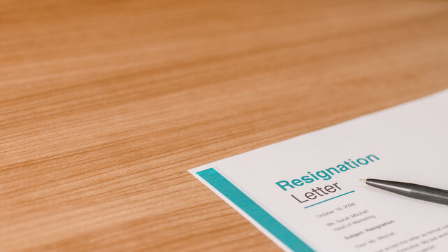 Professional resignation letter on a wooden desk with a pen. Concept of career change, job termination, quitting work, employment resignation and corporate office transition