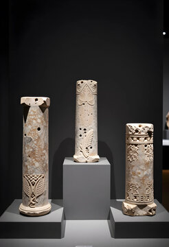 Ancient history and archaeology, carved stone columns and architectural artifacts on display in a museum exhibition with intricate historical carvings
