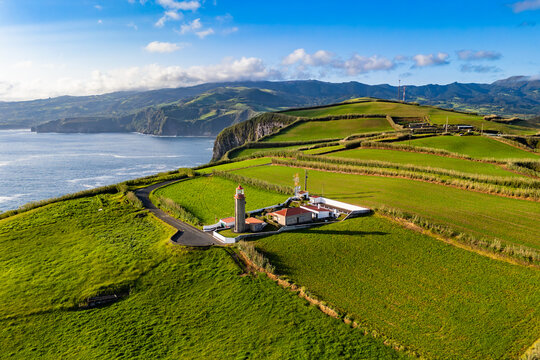 Coastal landscape with Cintrao lighthouse in bright green pastureland, Azores, Portugal