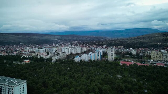 Aerial view of Blok 5 residential neighborhood and Toloska forest park in Podgorica, Montenegro with mountains in background