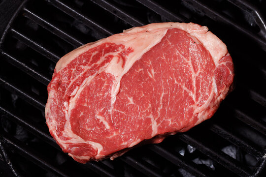 Raw marbled beef steak on grill