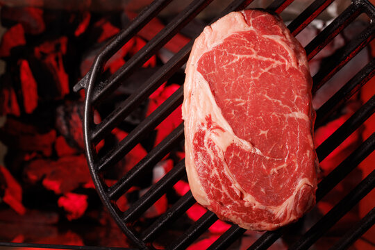 Vertical raw ribeye steak on grill