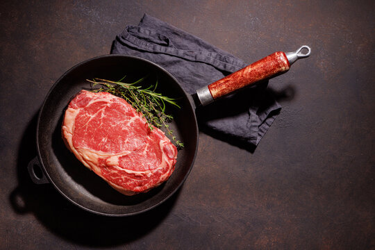 Raw ribeye steak in skillet with copy space