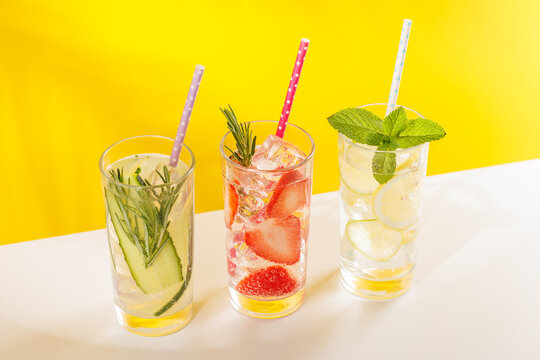 Set of fresh non alcoholic drinks with strawberry cucumber and lemon on yellow background