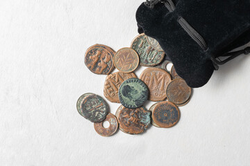 Ancient and historical coins spilling from black velvet pouch. Roman, Byzantine, and Mandatory Palestine coins © ArieStudio