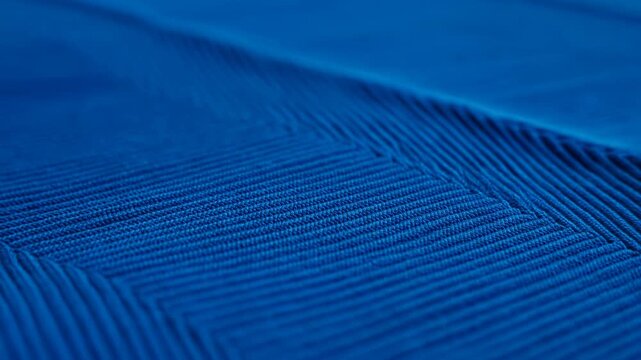Blue woven textile fibers form repeating ridges across an abstract close-up surface. Fashion design presentation, textile product, and abstract title.