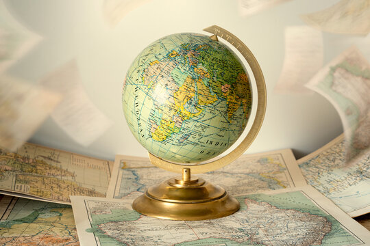 Antique old globe surrounded by vintage maps, evoking historical geography, exploration, travel, cartography, and the discovery of the world. 