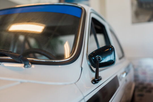 View of a white vintage car featuring a blue sun visor strip and a black side mirror in Koudekerke, Zeeland, Netherlands.
