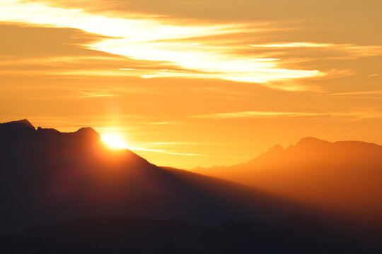 Goldener Sonnenaufgang &uuml;ber einer alpinen Berglandschaft mit markanten Silhouetten.