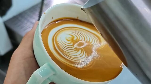 Barista Pouring Steamed Milk to Create Intricate Rosetta Latte Art in a Cup of Espresso
