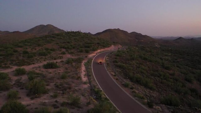 Car driving on winding desert road at dusk