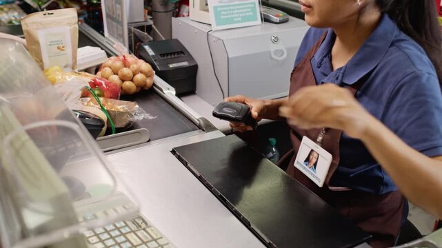 Young adult Hispanic woman cashier scanning groceries at supermarket checkout counter using barcode reader. Perfect for retail training, grocery store ads and commercial marketing