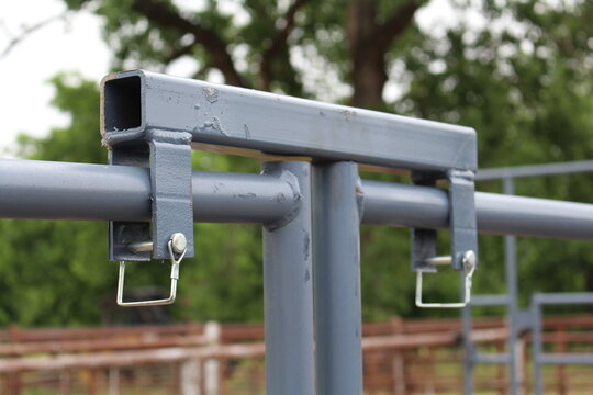 Close up of steel gate latch bracket with lynch pins on a pipe rail