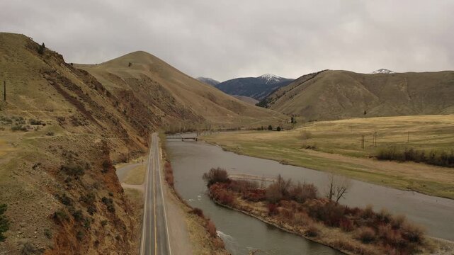 Aerial view of winding road and river through mountain valley