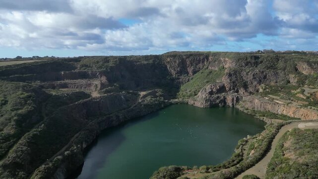 Penlee, Cornwall, England: DRONE VIEWS: The drone flies over Penlee quarry lake. Copper, zinc and crushed stone were once mined at the quarry, but the quarry has been dormant since the 1970s.