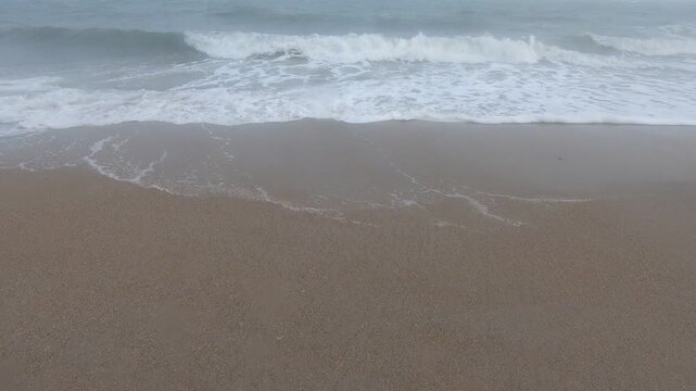 Waves washing onto sandy beach on a misty day