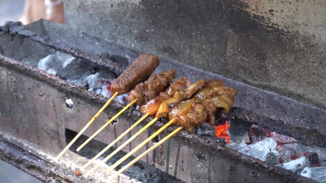 Traditional Indonesian satay kere skewered on bamboo sticks grilled over hot charcoal on street food vendor grill, authentic local culinary delicacy from Solo Central Java full of savory taste.