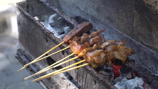 Traditional Indonesian satay kere skewered on bamboo sticks grilled over hot charcoal on street food vendor grill, authentic local culinary delicacy from Solo Central Java full of savory taste.