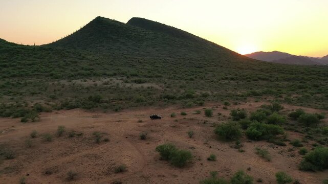 Aerial view of desert hills at sunrise with off-road vehicle