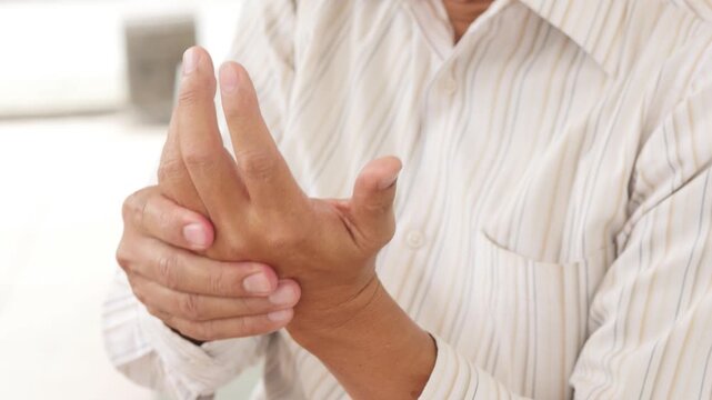 60s old east asian man massaging his hand and finger, home remedy concept, back of hand view