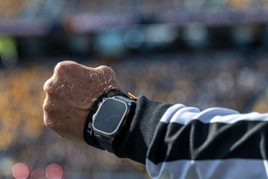 Referee Checking Watch During Football Game With Crowd in Blurred Stadium Background