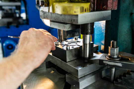 Metal component production with bending die and mechanical stamping press. Close-up of industrial tooling during sheet metal forming