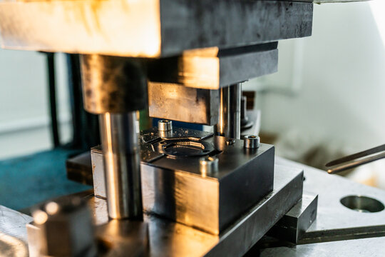 Industrial press bending metal components in factory workshop. Close-up of stamping equipment and metal parts manufacturing