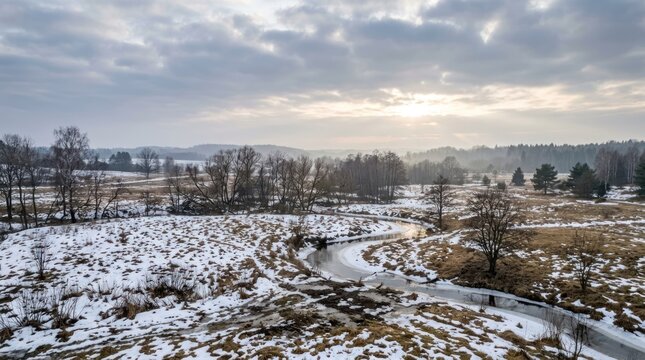 A serene winter landscape with snow-covered fields, trees, and a winding path, with a clear blue sky and a few scattered clouds overhead.