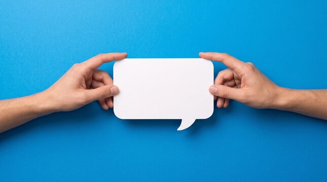 Two hands holding a blank white speech bubble against a blue background