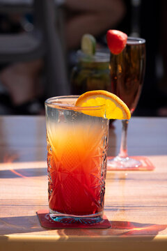 Tequila Sunrise and Rossini champagne cocktails served on a sunny outdoor restaurant table.