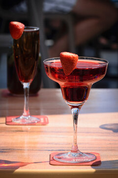 Gourmet strawberry champagne and rossini cocktails in coupe and flute glasses on a sunlit wooden table.