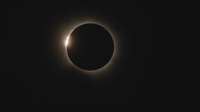 View of the total solar eclipse showing the diamond ring effect with a bright flare of light against the dark moon in the sky over Leon, Castile and Leon, Spain.