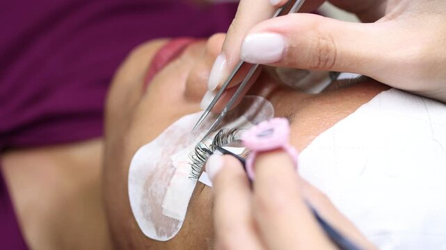 The process of eyelash extension and volume increase in a professional beauty salon, close-up view