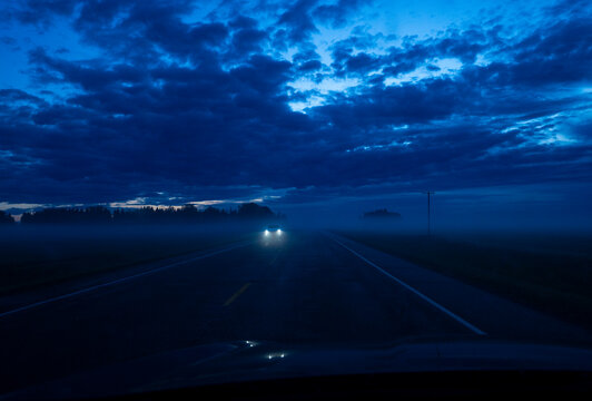 Fog Covers a Road at Twilight With Headlights Approaching