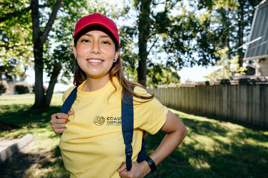 Smiling volunteer in yellow Coast Keepers shirt outdoors