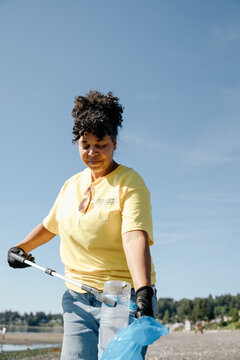 Volunteer woman cleaning beach during sunny community cleanup