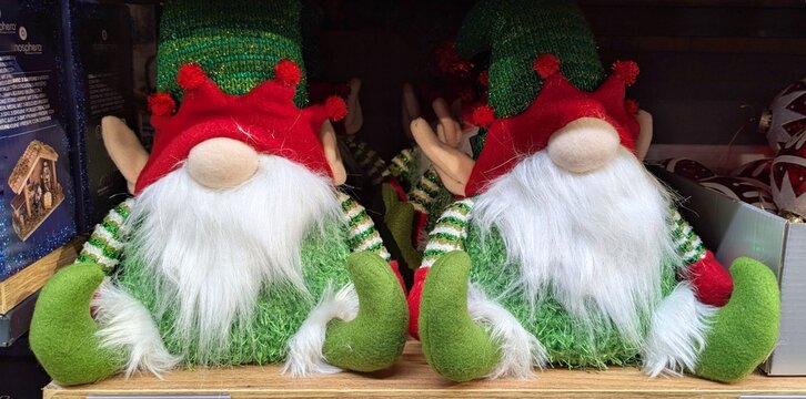 Tiempo de Navidad. Simp&aacute;ticos mu&ntilde;ecos de peluche de elfos de Santa Claus de grandes orejas, rodeados de decoraci&oacute;n navide&ntilde;a, sentados en el estante de una tienda