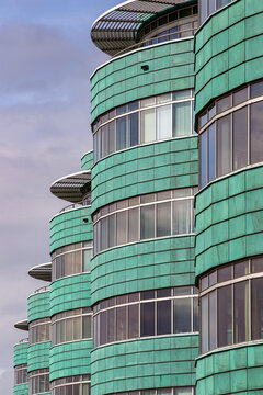 View of the curved green copper-clad facade of a modern building with large glass windows in Almere, Flevoland, Netherlands.