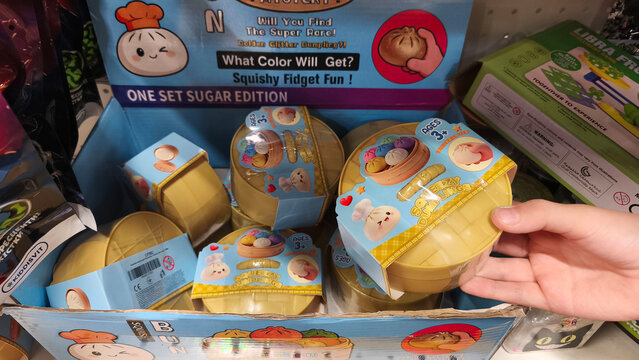Kyiv, Ukraine, October 19, 2026. A childs hand holds yellow container with trendy, tactile, anti-stress toys shaped like dumplings. collectible figures for stress relief and sensory play in a store
