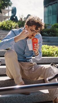 Man eats takeaway lunch on stone steps by bicycle against office