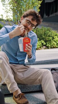 Man in glasses eats lunch behind bicycle on city office steps