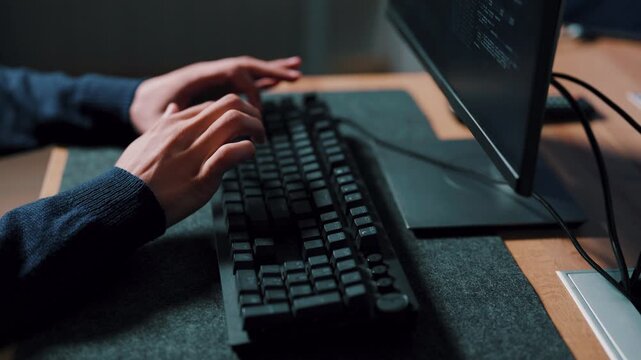 Programming work, close-up of developer hands typing code on keyboard at office desk at night