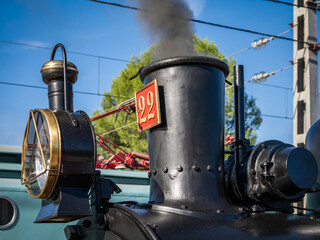 A beautifully restored black vintage steam locomotive stands outside its depot under a partially cloudy blue sky © @CMG_IG