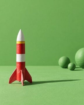 Model rocket painted red and white standing on a green surface with a satin finish and long shadows for World Space Week and STEM education