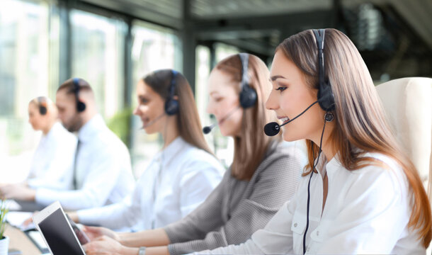 Portrait of call center worker accompanied by her team. Smiling customer support operator at work.