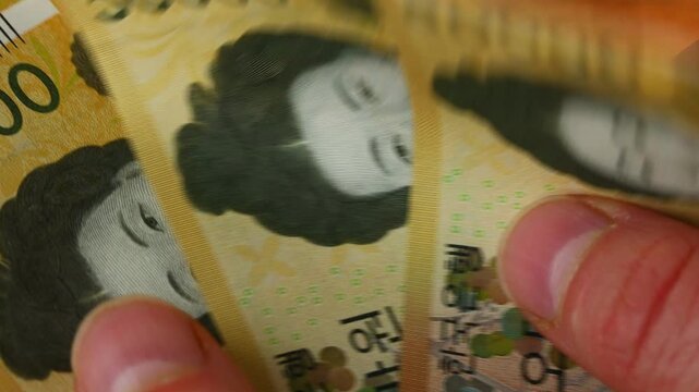 South Korea money. Macro close up of Korean Won being counted by hand. Paper banknotes of 50000 won denominations. KRW currency symbol. Financial and business concept