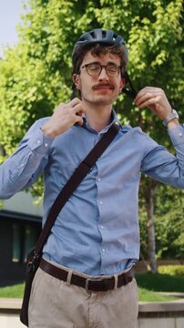 Focused man adjusts helmet at bicycle near modern office plaza