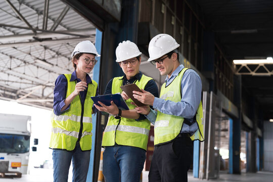 Workers, warehouse storage and logistics. Diverse group of warehouse workers wearing safety hard hats discussing inventory management and operations logistics planning in industrial storage warehouse