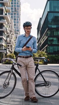 Man looks around standing near bicycle in modern office plaza