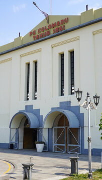 Historic De Tjolomadoe sugar factory facade in Karanganyar, Indonesia. Restored colonial Dutch architecture landmark featuring cream walls, arched doors, and vintage lamps on sunny clear day.
